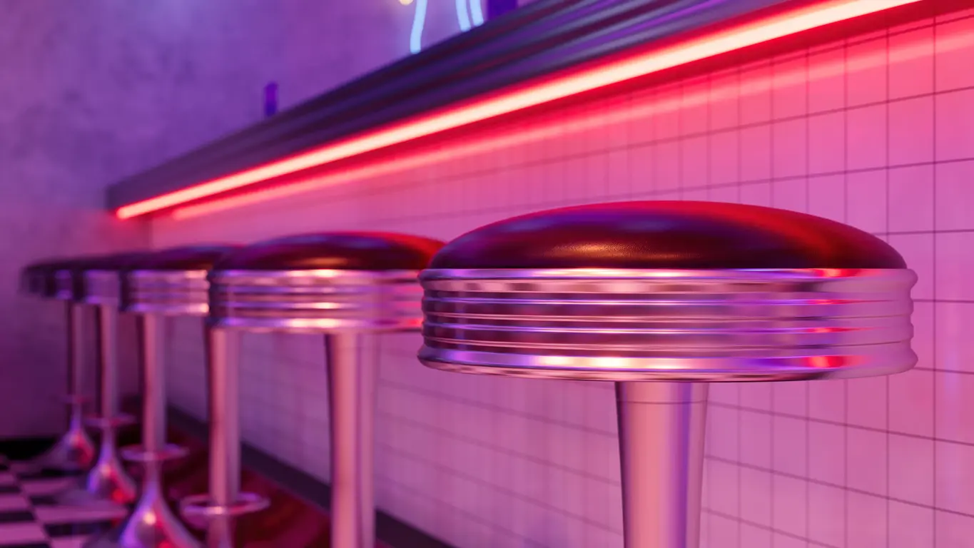Row of chrome pedestal bar stools fixed close under a neon-lit counter edge