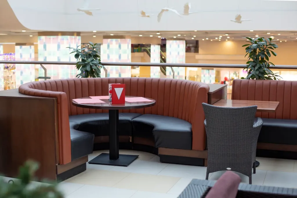 Corner booth seating in a half-round unit with a curved fluted back and a round table on a column base