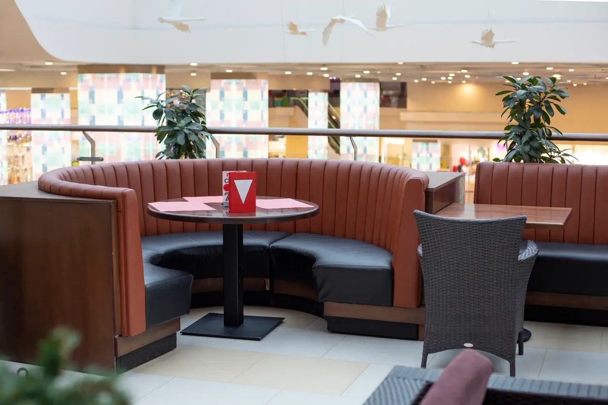 Corner booth seating in a half-round unit with a curved fluted back and a round table on a column base