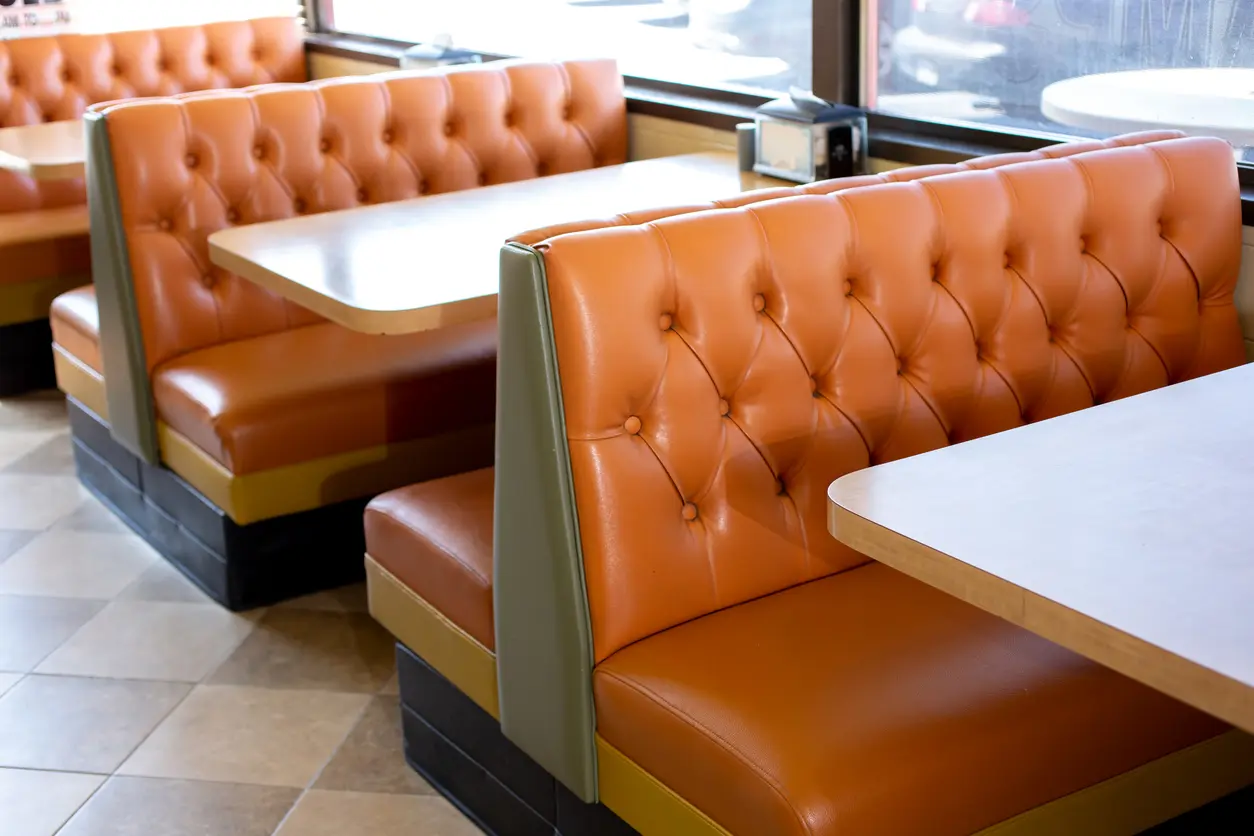 Buttoned leather booth backs with laminate table tops, showing the gap between seat front and table edge