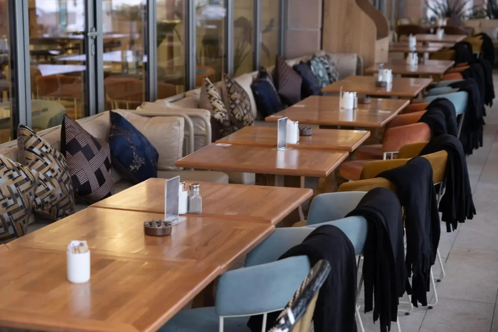 Row of rectangular timber restaurant tables along a banquette in a finished dining room