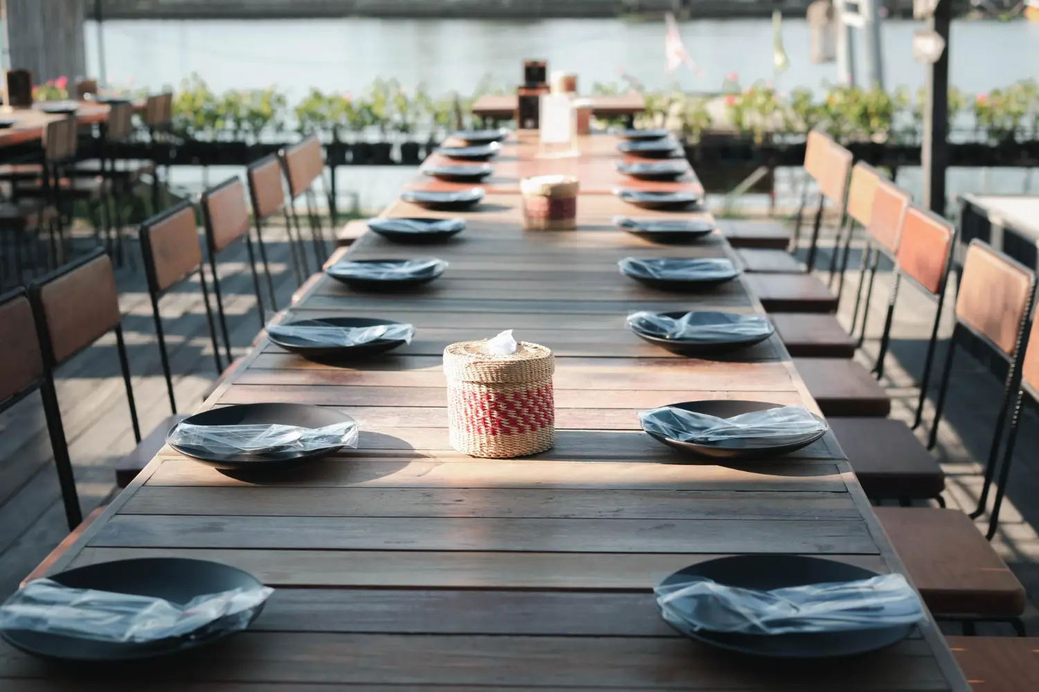 Long communal restaurant table laid with evenly spaced place settings and side chairs down both sides